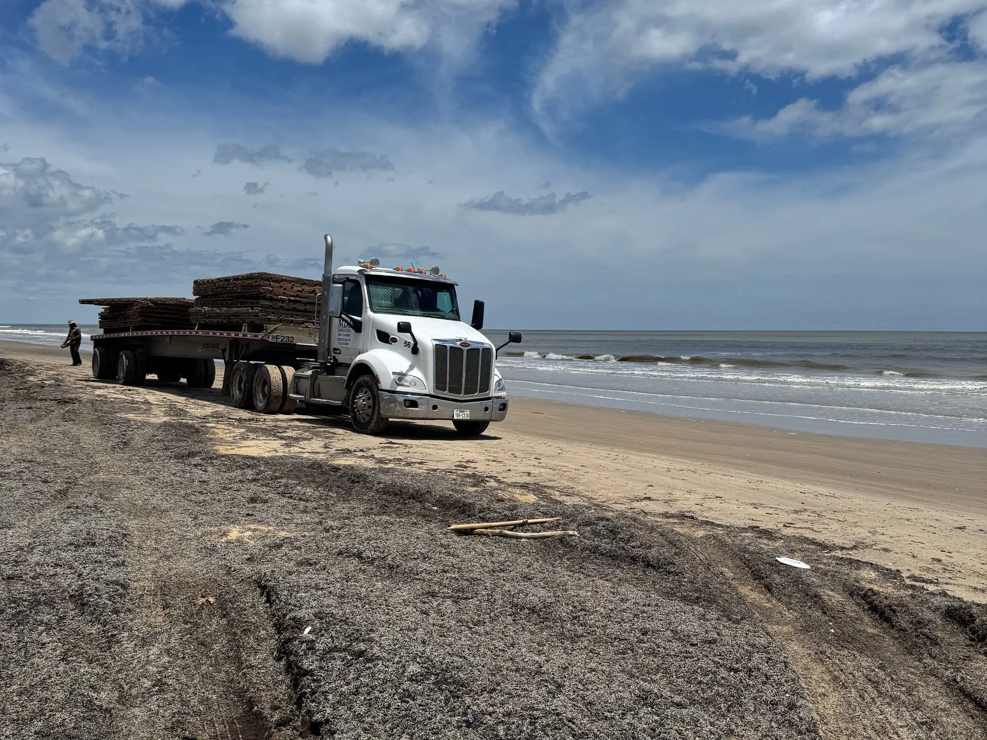 MDJ Services flatbed truck hauling mats on the sand at McFaddin Beach on the Southeast Texas coast